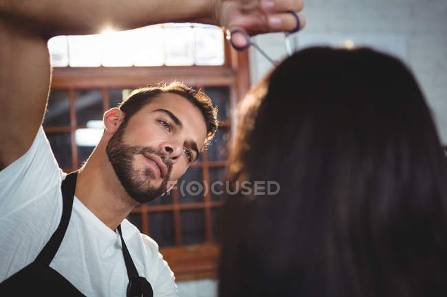 Женщине стригут волосы ножницами в салоне — стоковое фото