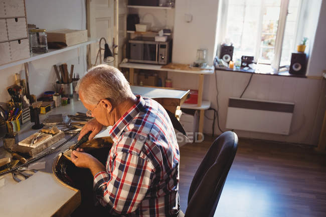 Attentive goldsmith using hand piece machine in workshop — Stock Photo
