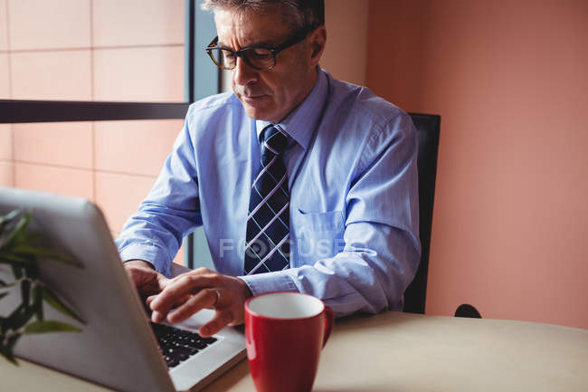 Бизнесмен, работающий над ноутбуком в офисе — стоковое фото