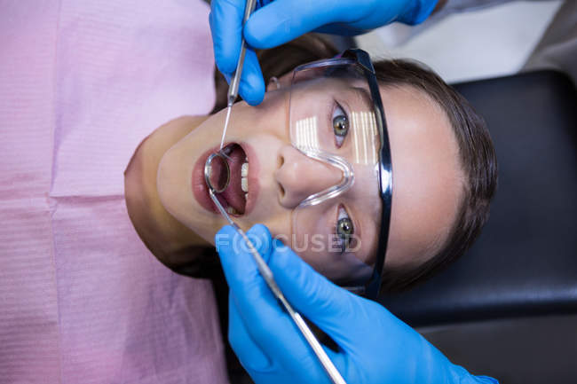 Dentiste examinant un jeune patient avec des outils à la clinique dentaire — Photo de stock