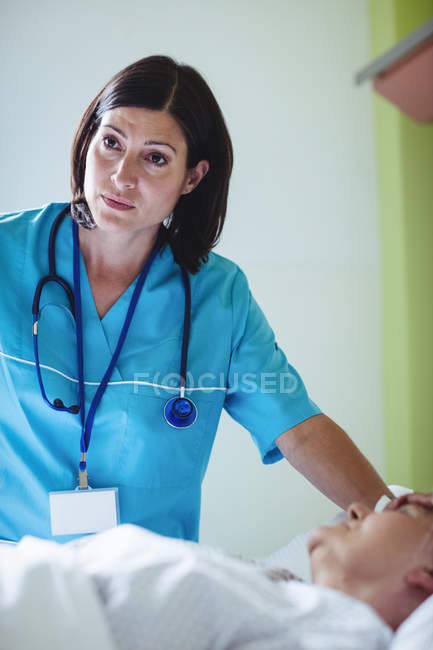 Enfermeira a verificar paciente sénior na enfermaria do hospital — Fotografia de Stock