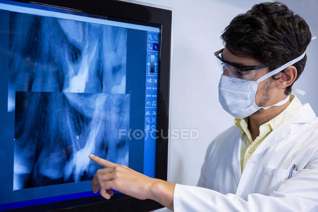 Дантист осматривает рентген на мониторе в клинике — стоковое фото