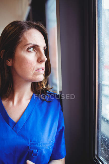 Enfermeira olhando para a janela do hospital — Fotografia de Stock