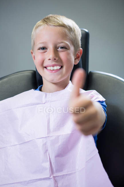 Lächelnder junger Patient zeigt in Zahnarztpraxis Daumen hoch — Stockfoto