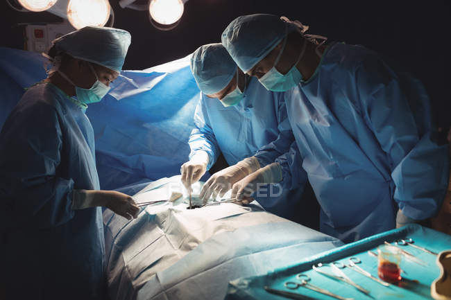 Cirujanos realizando operación en quirófano en el hospital - foto de stock