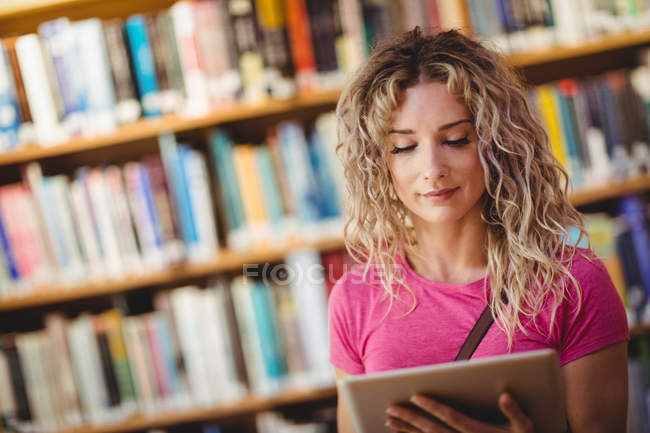 Mulher usando tablet digital na biblioteca — Fotografia de Stock