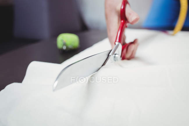 Imagem recortada do designer de moda feminina cortando tecido branco em estúdio — Fotografia de Stock