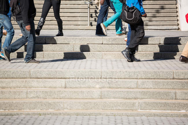 Section basse de personnes montant les escaliers à la lumière du jour — Photo de stock