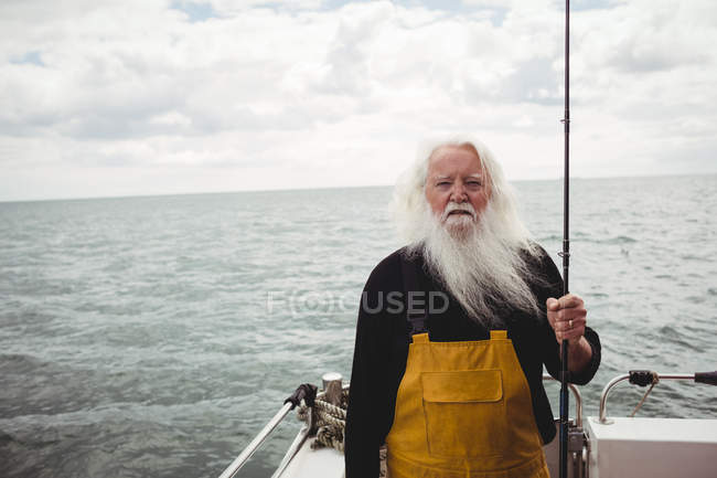 Retrato del pescador de pie en el barco sosteniendo caña de pescar - foto de stock