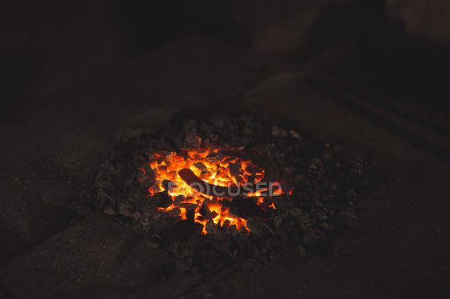 Metallhufeisen wird in der Schmiede auf Kohlen bei der Arbeit erhitzt — Stockfoto