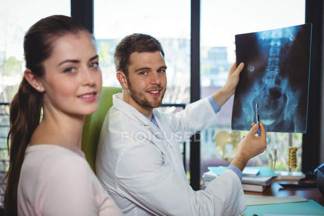 Male therapist showing x-ray to female patient in clinic — Stock Photo