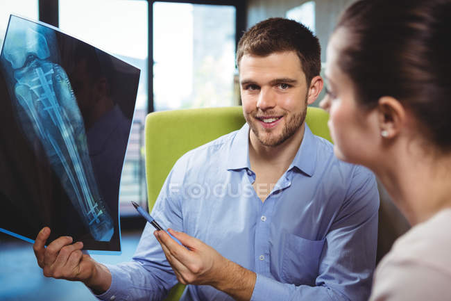 Portrait of physiotherapist explaining leg x-ray to female patient in clinic — Stock Photo