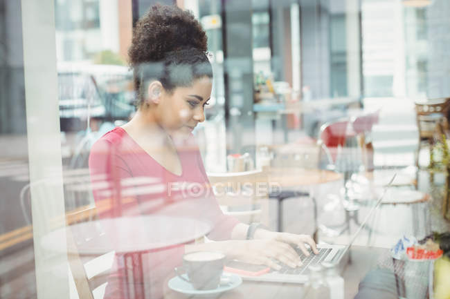 Складене зображення молоду жінку, використовуючи ноутбук у місті — стокове фото