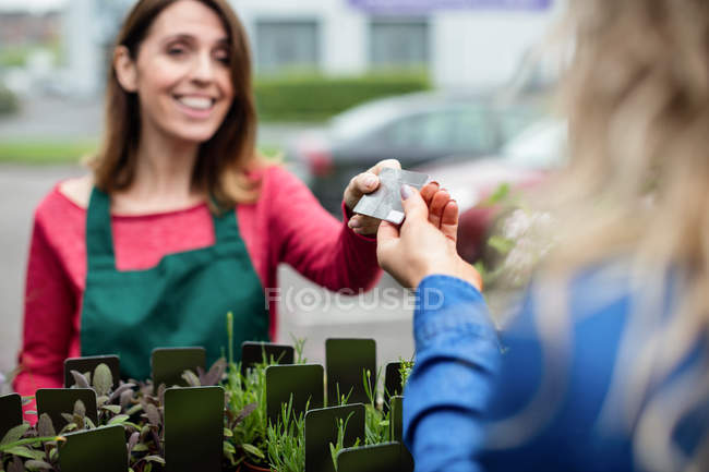 Frau zahlt mit Kreditkarte bei Blumengeschäft im Gartencenter — Stockfoto