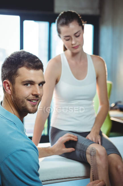 Terapeuta do sexo masculino medindo joelho paciente feminino com goniômetro na clínica — Fotografia de Stock