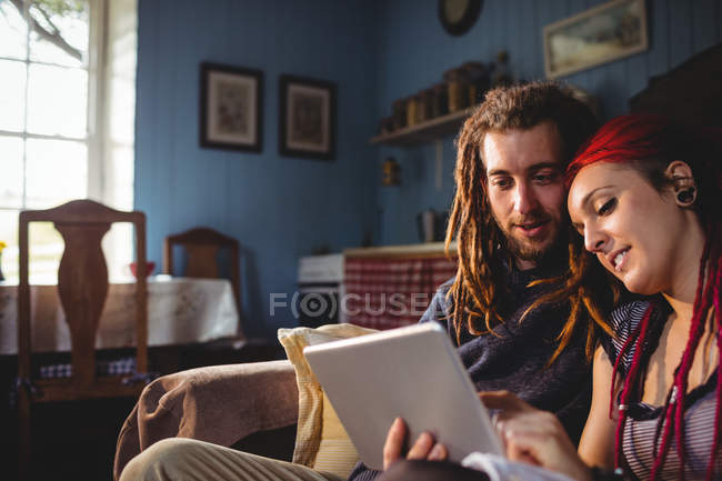 Couple hipster romantique utilisant une tablette numérique tout en étant assis à la maison — Photo de stock