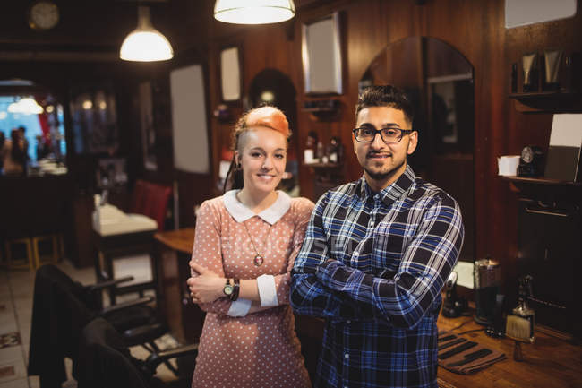 Portrait of two barbers standing with arm crossed in barber shop — Stock Photo