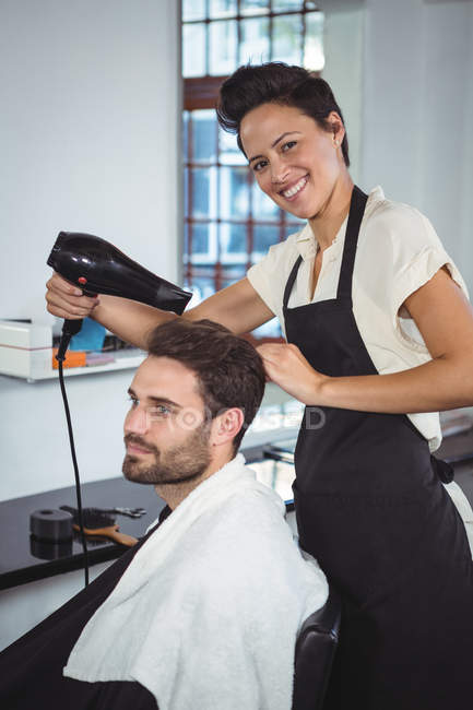 Мужчина высушивает волосы феном в салоне — стоковое фото