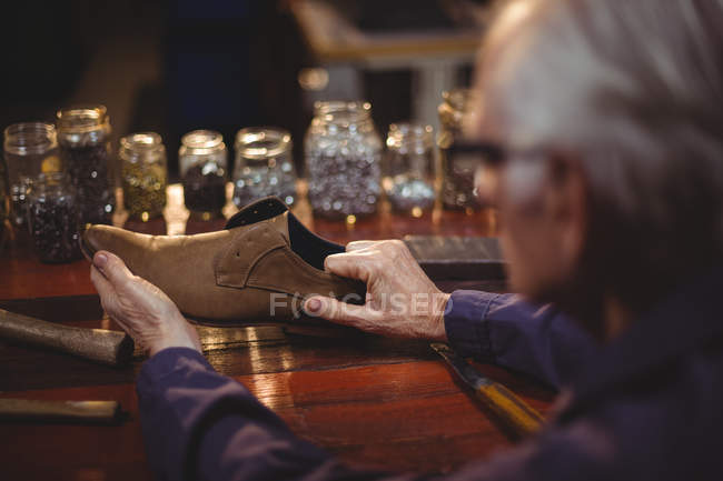 Обувщик осматривает обувь в мастерской — стоковое фото