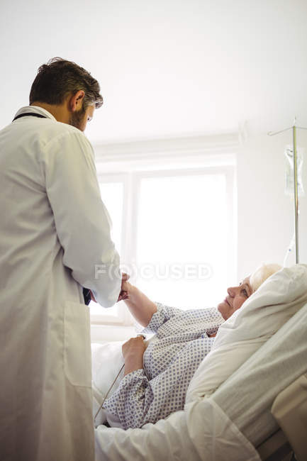 Médico masculino examinando a una mujer mayor en el hospital - foto de stock