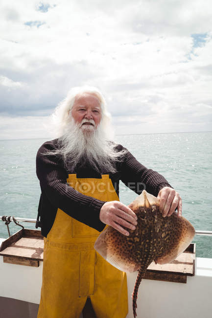 Portrait of fisherman holding ray fish on boat — Stock Photo