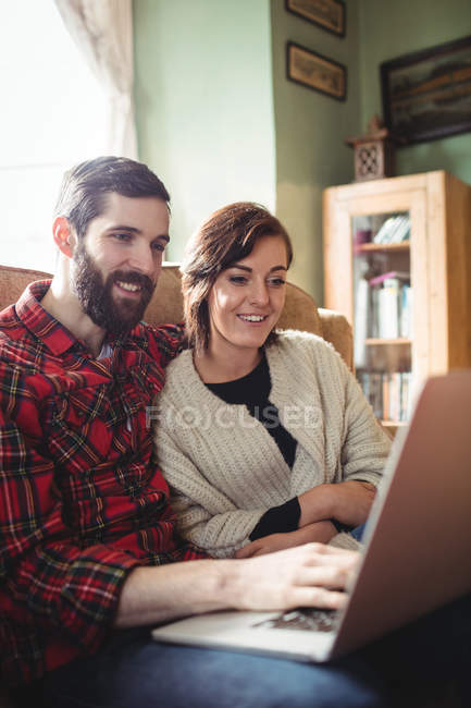 Jeune couple utilisant un ordinateur portable dans le salon à la maison — Photo de stock