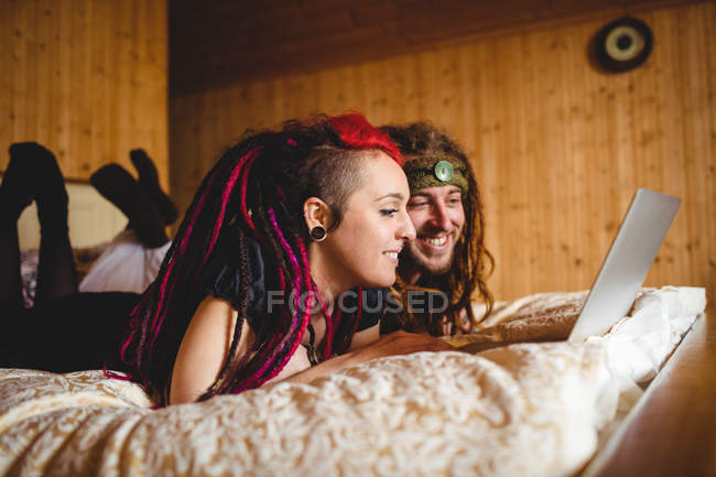 Усміхаючись молодої пари, використання ноутбука на ліжку у себе вдома — стокове фото