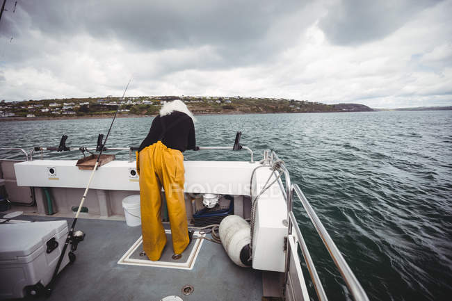 Rückansicht des Fischers, der vom Fischerboot ins Meer blickt — Stockfoto