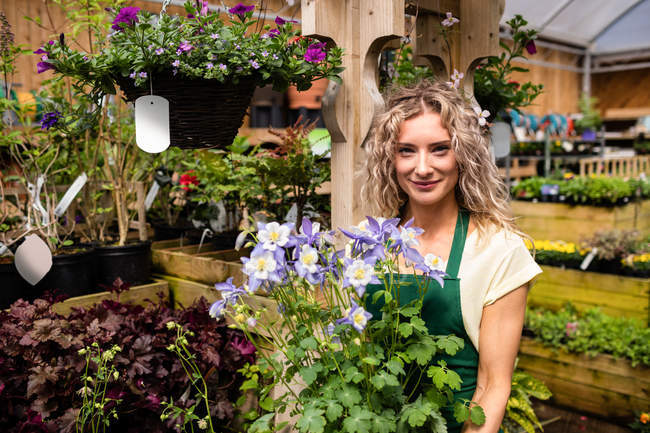 Портрет жіночого флориста, що тримає горщики в садовому центрі — стокове фото