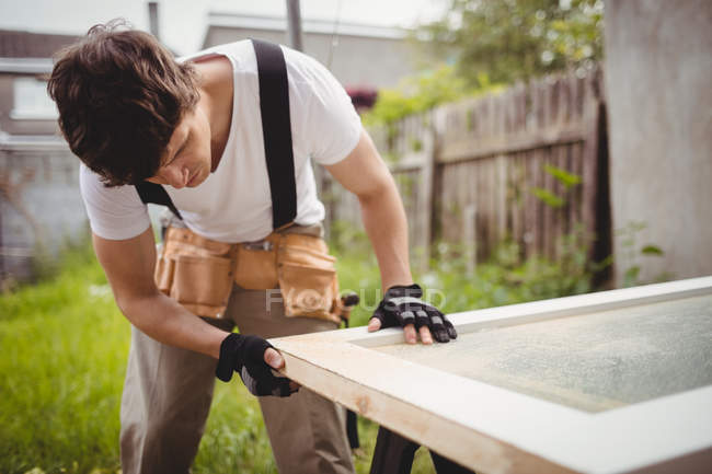 Carpinteiro trabalhando na moldura da porta no gramado — Fotografia de Stock