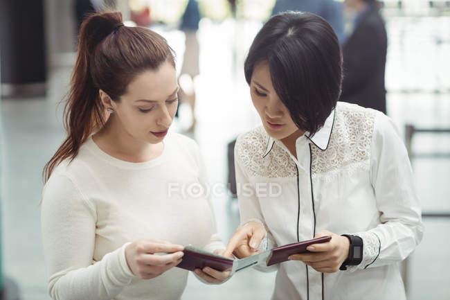 Two women checking their passports in airport terminal — Stock Photo