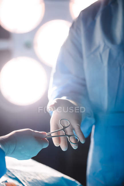 Chirurgo che dà forbici operazione al collega in sala operatoria in ospedale — Foto stock