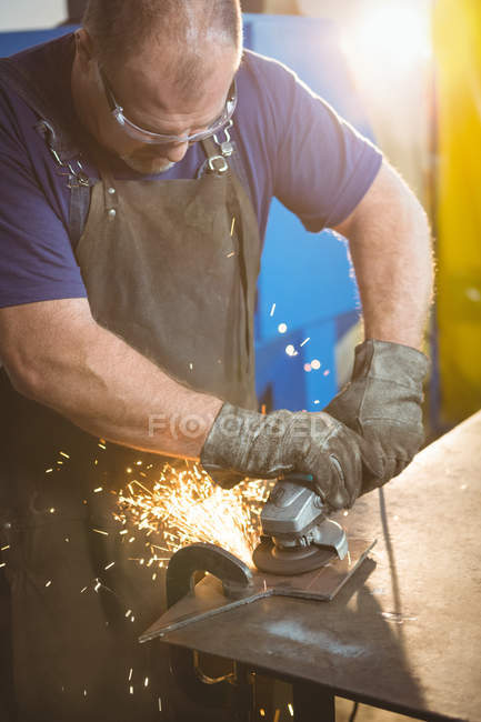 Welder cutting metal with electric tool in workshop — Stock Photo