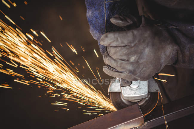 Image recadrée du soudeur coupant le métal avec l'outil électrique en atelier — Photo de stock