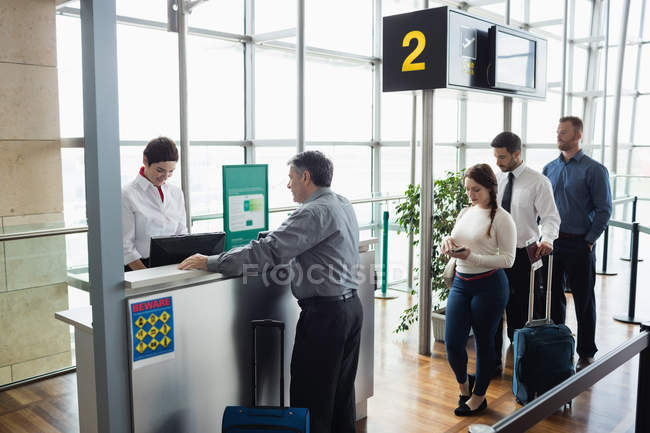 Passagiere stehen am Check-in-Schalter im Flughafenterminal Schlange — Stockfoto