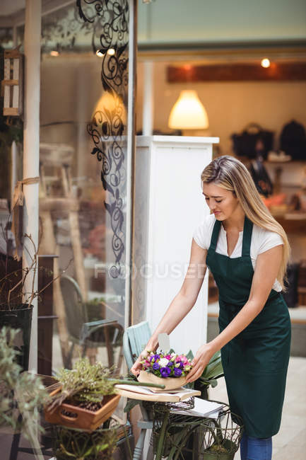 Fiorista femminile che organizza mazzo di fiori in espositore di fiori al negozio di fiori — Foto stock
