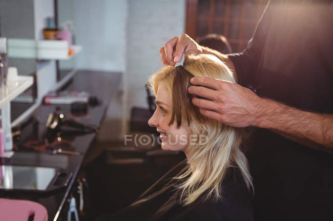 Мужчина парикмахер укладки клиентов волосы в салоне — стоковое фото