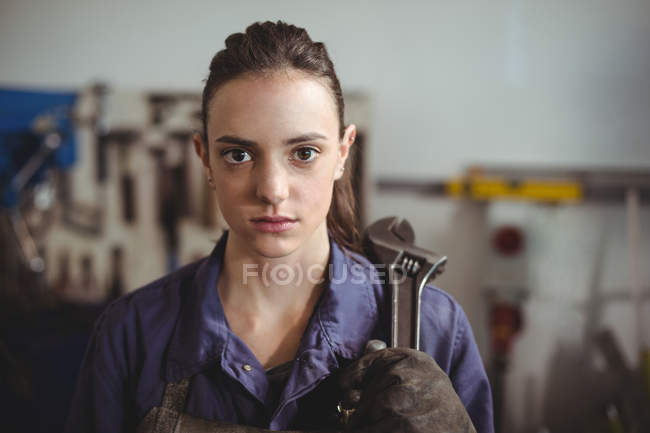 Soldador hembra que sostiene la herramienta de la llave inglesa en taller - foto de stock