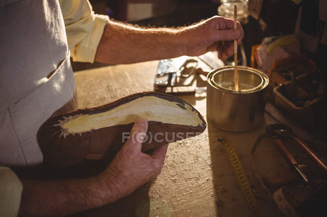 Primer plano del zapatero aplicando pegamento en la suela del zapato en el taller - foto de stock