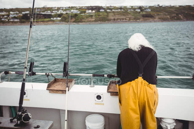 Vue arrière du pêcheur regardant dans la mer depuis un bateau de pêche — Photo de stock