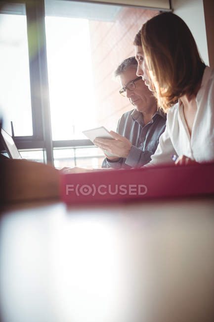 Hombre y mujer discutiendo sobre tableta digital y portátil en la oficina - foto de stock
