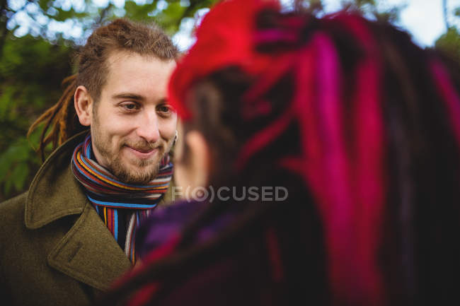 Hipster sorridente guardando la donna mentre in piedi nel parco — Foto stock