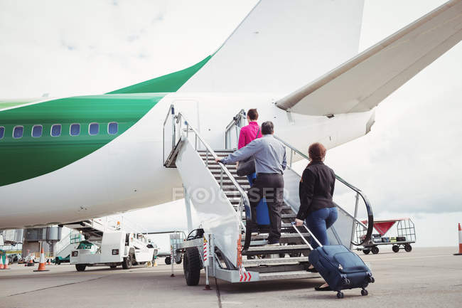 Pasajeros subiendo por las escaleras y entrando en el avión en el aeropuerto - foto de stock