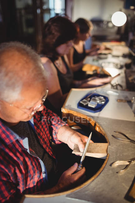 Фокусований старший чоловік золотошукач формує деревину в майстерні — стокове фото