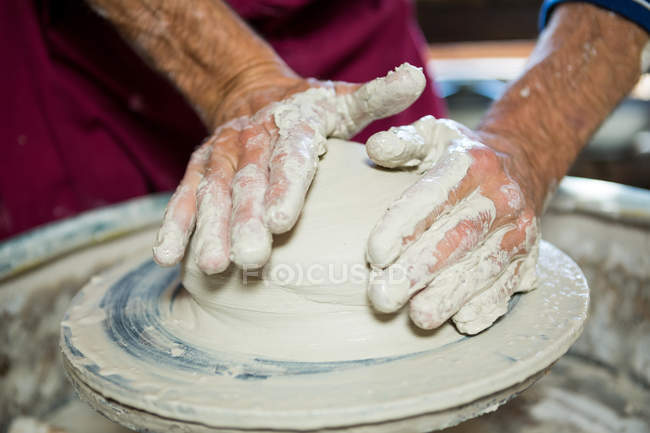 Sección media de alfarero haciendo olla en taller de cerámica - foto de stock