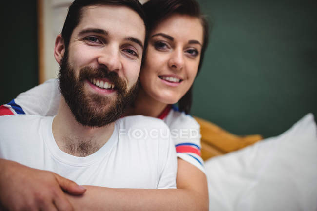 Donna che abbraccia l'uomo sul letto in camera da letto — Foto stock