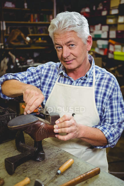 Uomo anziano calzolaio riparazione di una scarpa in officina — Foto stock