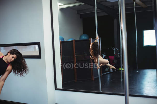 Atractiva bailarina polaca practicando pole dance en gimnasio - foto de stock