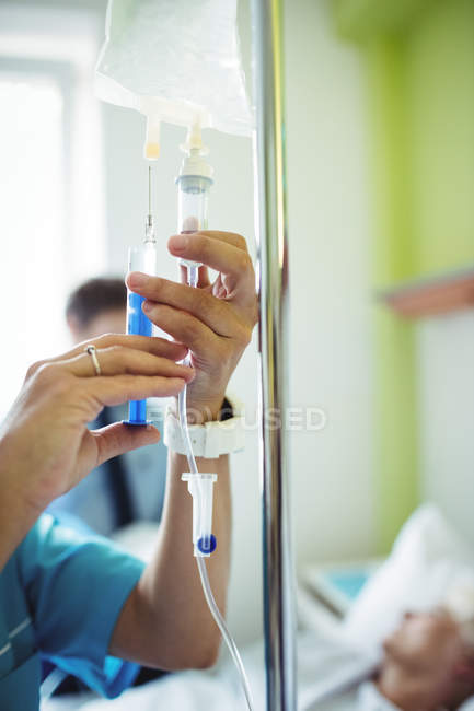Руки медсестры, вводящей лекарства в инфузию в больнице — стоковое фото