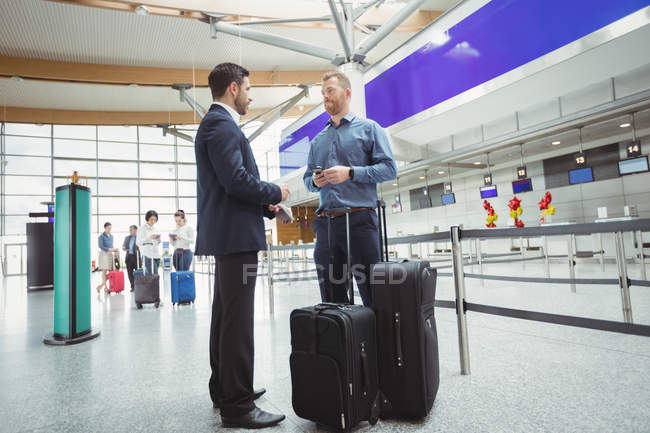 Empresários esperando no balcão de check-in com bagagem no terminal do aeroporto — Fotografia de Stock